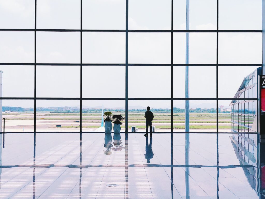 man looking out of window at airport
